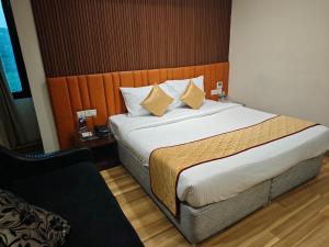 a bedroom with a large bed with a wooden headboard at Esthell Hotel in Chennai