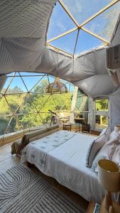 a bed in a tent with a large window at Soul Forest GeoDome - Off-grid Nature Escape in Sedgefield