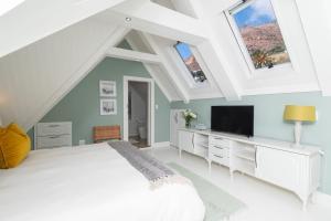 a bedroom with a white bed and a tv at The Willets Boutique Hotel in Simonʼs Town