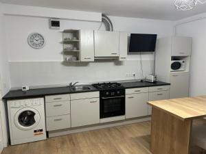 a white kitchen with a stove and a dishwasher at Central Apartment in Zalău +9 photos