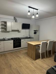 a kitchen with white cabinets and a wooden table at Central Apartment in Zalău