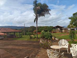 a patio with a table and chairs and a palm tree at Recanto do Sitio in Tiradentes