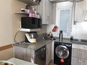 a kitchen with a microwave and a washing machine at O Xuncal in San Cosme de Barreiros
