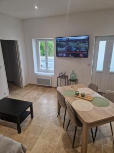 a living room with a table and a tv on the wall at Gîte pour 2 personnes in Le Bugue