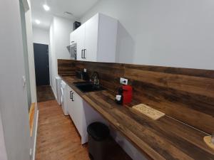 a kitchen with white cabinets and a wooden counter top at Charmant studio cosy - Hyper centre in Saint-Gaudens