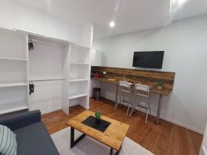 a living room with a desk and a tv on a wall at Charmant studio cosy - Hyper centre in Saint-Gaudens