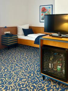 a hotel room with a bed with a flat screen tv at Hotel am Kurpark in Schönebeck
