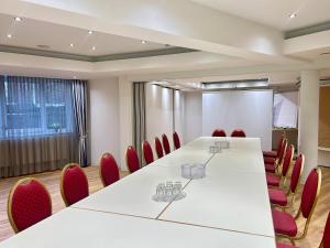 a conference room with a long table and red chairs at Hotel am Kurpark in Schönebeck