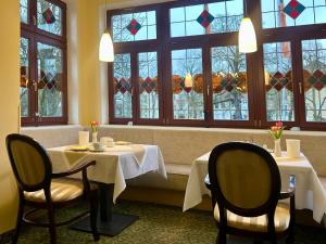 two tables and chairs in a restaurant with windows at Hotel am Kurpark in Schönebeck