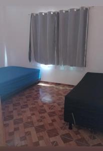a room with a bed and a window with a curtain at Recanto Soares in Mucuri