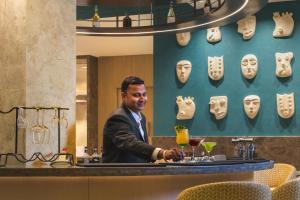 a man standing behind a bar with masks on the wall at Hotel Gwalior Regency, a member of Radisson Individuals in Gwalior