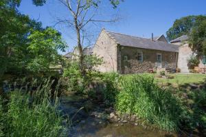 an old stone house with a stream in front of it at 1 Bed in Lowick oc-coq44 in Holburn