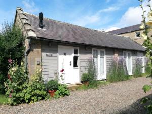 a cottage with a white garage and some flowers at 1 Bed in Lowick oc-coq46 in Holburn