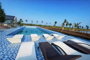 a swimming pool with chaise lounges and chairs at Balat Resort in Tập Thiện