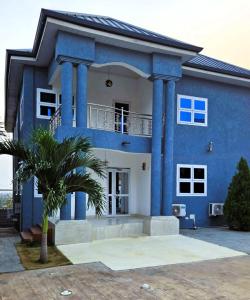 a blue house with a palm tree in front of it at The Basileia Court in Janman