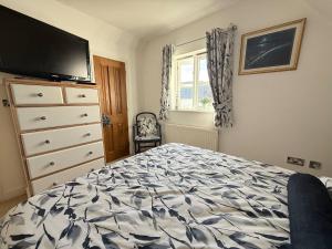 a bedroom with a bed and a dresser with a tv at Our Garden View Room in Bedford