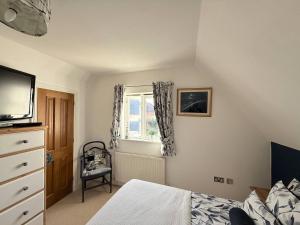 a bedroom with a bed and a tv and a window at Our Garden View Room in Bedford