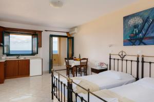a bedroom with two beds and a kitchen and a table at Archipelagos Apartments in Arkasa