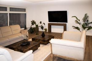 a living room with white furniture and a flat screen tv at Lucky Strike Hostel in Bad Oldesloe
