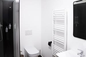 a white bathroom with a toilet and a tv at Lucky Strike Hostel in Bad Oldesloe