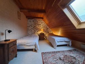 a attic room with two beds and a window at Nouveau - Maison Nierveze proche Lioran in Thiézac