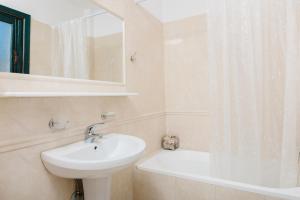 a white bathroom with a sink and a bath tub at Archipelagos Apartments in Arkasa