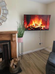 a living room with a fireplace with a tv on the wall at Carrickasticken House in Dungooly Cross Roads