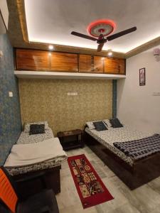 two beds in a room with a ceiling fan at ROOMS vala in Varanasi