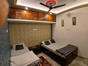 a room with two beds and a ceiling fan at ROOMS vala in Varanasi +6 photos