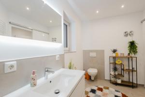 a white bathroom with a sink and a toilet at "Happy Vibes" City Appartment in Passau +26 photos