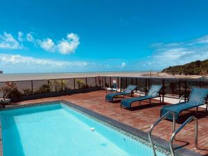 a swimming pool on a balcony with chairs and the beach at Loft 306 Imperial Suites in João Pessoa
