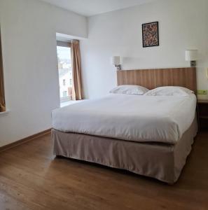 a bedroom with a large white bed with a window at Le Grand Hôtel Ussel ''nouvelle Gérance 2023'' in Ussel