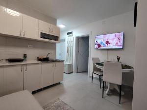 a kitchen with white cabinets and a dining room at Apartman Pavlica in Kragujevac