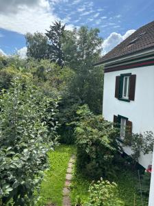 a garden next to a white house with bushes at Zimmer mit Aussicht, Gstaltenrain 19 in Kaiseraugst