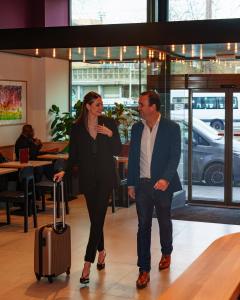 a man and a woman walking with a suitcase at Jill Hotel Brussels Centre Midi in Brussels
