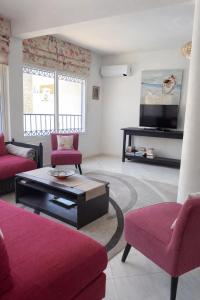 a living room with red chairs and a tv at Villa grand large in Tamraght Ouzdar
