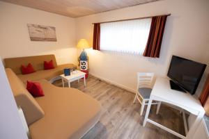 a small living room with a couch and a television at Hotel Anka in Norddorf +50 photos