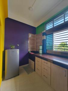 a kitchen with purple and green walls and a refrigerator at Aashray Independent Homestay Dibrugarh in Dibrugarh