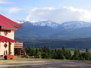 a building with a red roof with mountains in the background at Tschurtschenthaler Lodge in Golden