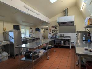a large kitchen with tables and appliances in it at Magdalen The Old Dairy in Winsham +6 photos