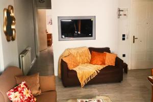 a living room with a brown couch with orange pillows at Sotiris Urban Stay in Xanthi