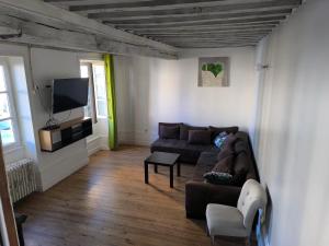 a living room with a couch and a tv at Chez Marine & Justine in Charolles