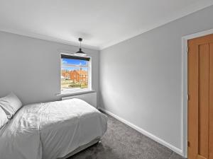 a white bedroom with a bed and a window at Modern Contractor House - Lockable Gated Parking in Kiveton Park