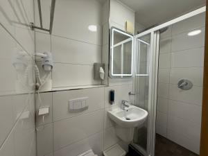 a white bathroom with a sink and a mirror at Shin Central Self-Check-in in Essen