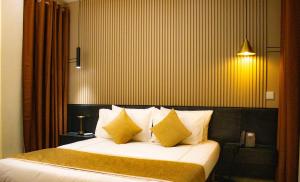 a bedroom with a bed with yellow and white pillows at Résidence PLAZZAET OUAGA 2000 in Ouagadougou +31 photos