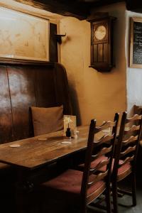 a wooden table with chairs and a clock on the wall at The Half Moon Inn in Dean