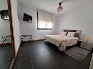 a white bedroom with a bed and a television at Aldea Bricia 201 in Posada de Llanes