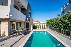 a swimming pool with a table and chairs next to a building at Villa Tamaris- 10 mins from Zadar in Zadar