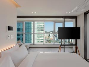 a bedroom with a white bed and a flat screen tv at 센텀 뉴시즈 호텔 in Millak-tong