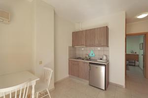 a kitchen with wooden cabinets and a table and chairs at Fenix Apartments in Mola Kalyva